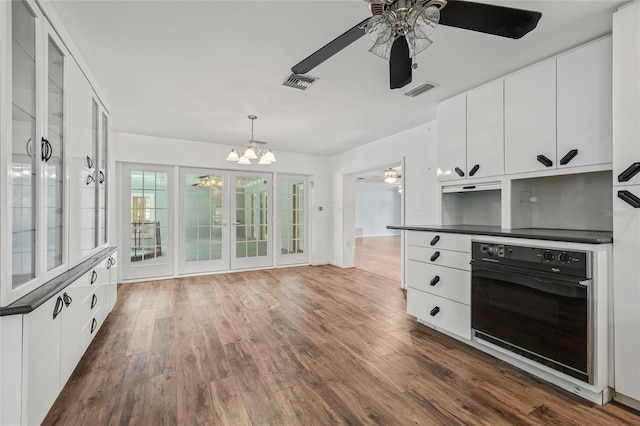 6103 6th Ave NW, Bradenton, FL 34209 - kitchen featuring black oven, dark countertops, ceiling fan, a chandelier, and white cabinetry