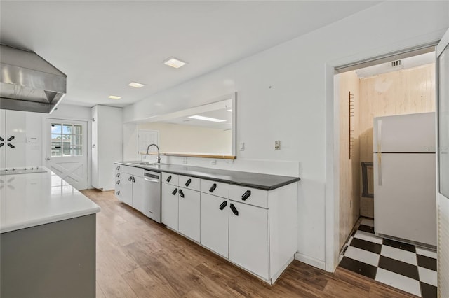 6103 6th Ave NW, Bradenton, FL 34209 - kitchen with freestanding refrigerator, stainless steel dishwasher, white cabinetry, tile patterned floors, and wall chimney range hood