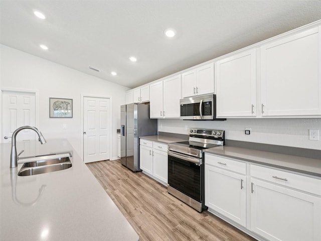6528 166th Pl E, Parrish, FL 34219 - kitchen featuring stainless steel appliances, lofted ceiling, recessed lighting, white cabinets, and light wood-style flooring