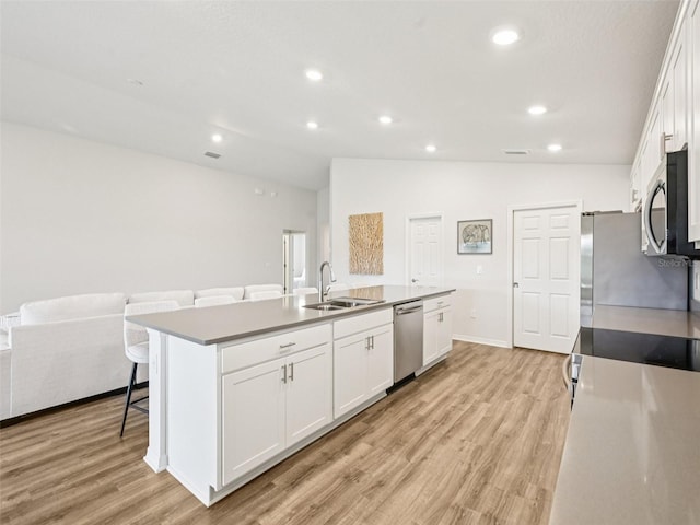 6528 166th Pl E, Parrish, FL 34219 - kitchen featuring stainless steel appliances, a kitchen island with sink, vaulted ceiling, white cabinets, and recessed lighting