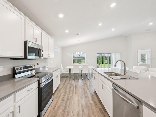 6528 166th Pl E, Parrish, FL 34219 - kitchen with stainless steel appliances, lofted ceiling, light wood-style floors, white cabinetry, and recessed lighting