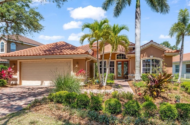 7521 Aralia Way, Seminole, FL 33777 - mediterranean / spanish home with stucco siding, a garage, french doors, driveway, and a tile roof