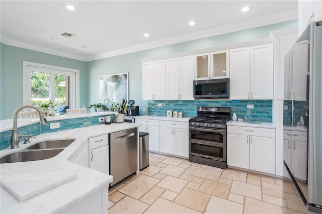 7521 Aralia Way, Seminole, FL 33777 - kitchen with appliances with stainless steel finishes, light countertops, backsplash, white cabinetry, and ornamental molding