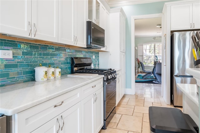7521 Aralia Way, Seminole, FL 33777 - kitchen with freestanding refrigerator, range with gas stovetop, crown molding, stone tile floors, and light countertops