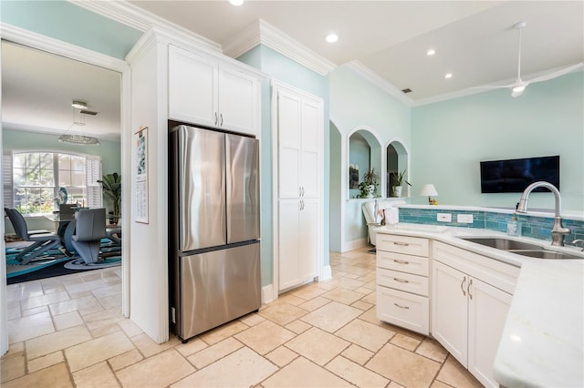 7521 Aralia Way, Seminole, FL 33777 - kitchen featuring freestanding refrigerator, ornamental molding, stone tile flooring, white cabinetry, and tasteful backsplash
