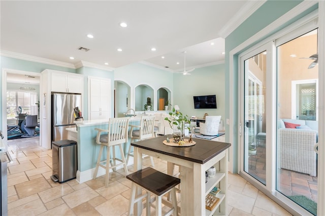 7521 Aralia Way, Seminole, FL 33777 - kitchen featuring freestanding refrigerator, crown molding, white cabinets, a breakfast bar area, and recessed lighting
