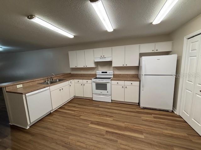 888 W Stuart St, Bartow, FL 33830 - kitchen featuring white appliances, a textured ceiling, under cabinet range hood, white cabinetry, and dark wood-style floors
