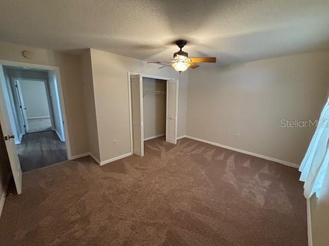 888 W Stuart St, Bartow, FL 33830 - unfurnished bedroom featuring dark carpet, a closet, a ceiling fan, and a textured ceiling