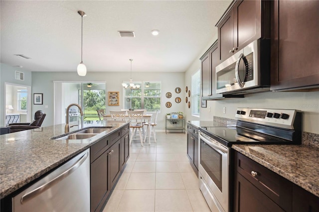 13804 Woodbridge Ter, Lakewood Ranch, FL 34211 - kitchen with appliances with stainless steel finishes, dark brown cabinets, dark stone counters, and decorative light fixtures