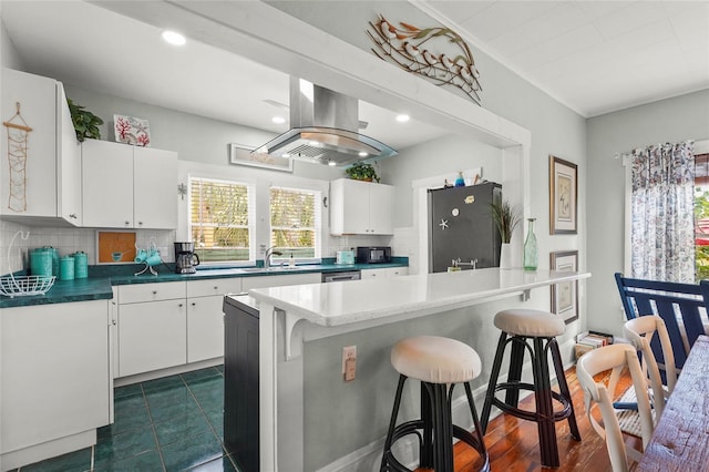 403 29th St NW, Bradenton, FL 34205 - kitchen with fridge, backsplash, white cabinets, a breakfast bar, and island exhaust hood