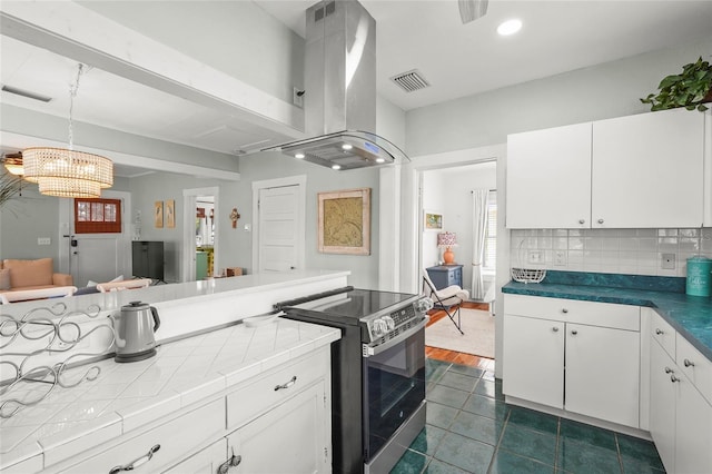 403 29th St NW, Bradenton, FL 34205 - kitchen featuring electric stove, island exhaust hood, white cabinetry, a chandelier, and dark tile patterned floors