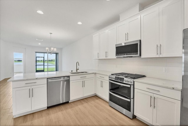 17823 Cherished Loop, Bradenton, FL 34211 - kitchen featuring stainless steel appliances, a peninsula, light wood-style floors, white cabinetry, and tasteful backsplash