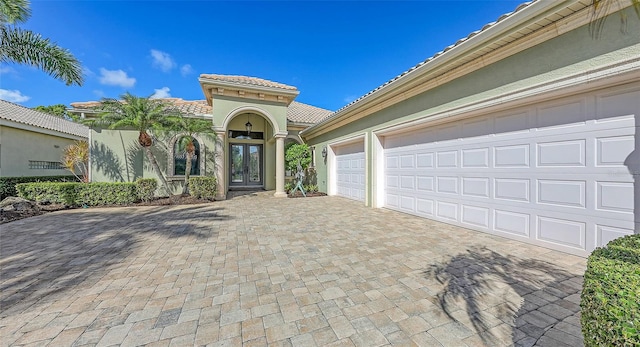 8832 Enclave Ct, Sarasota, FL 34238 - view of front facade featuring french doors, decorative driveway, a tile roof, and stucco siding