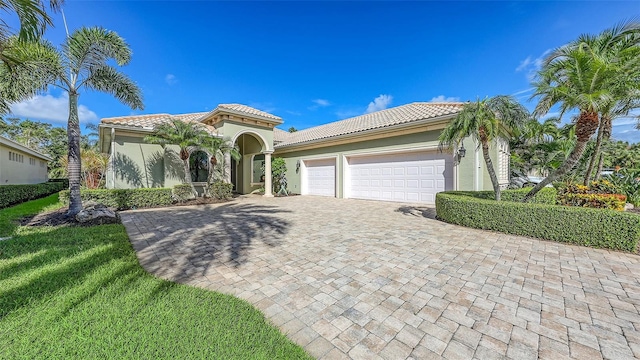 8832 Enclave Ct, Sarasota, FL 34238 - mediterranean / spanish-style house with decorative driveway, stucco siding, a tiled roof, and an attached garage