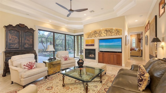 8832 Enclave Ct, Sarasota, FL 34238 - living area with ceiling fan, a tray ceiling, ornamental molding, a glass covered fireplace, and light tile patterned floors