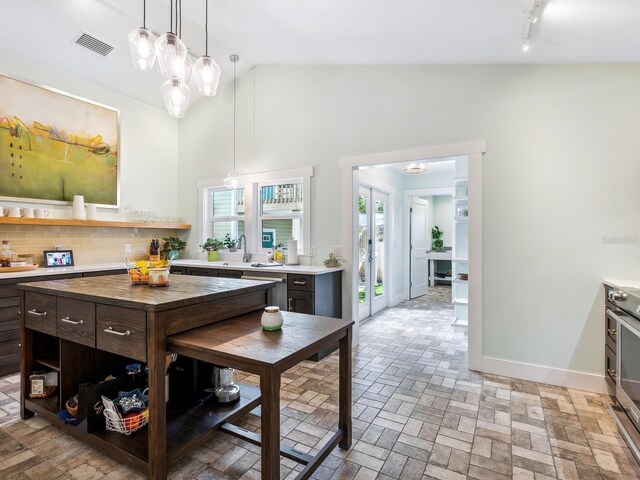 1732 6th St, Sarasota, FL 34236 - kitchen featuring light countertops, open shelves, decorative light fixtures, vaulted ceiling, and brick patterned flooring
