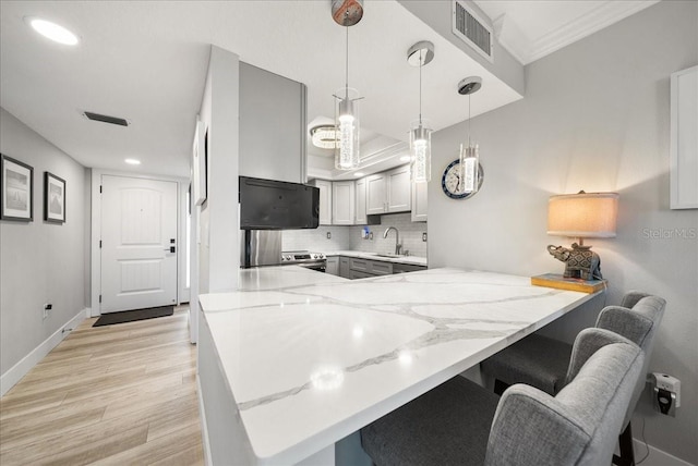 8750 Midnight Pass Rd Unit 501, Sarasota, FL 34242 - kitchen featuring a peninsula, light stone countertops, backsplash, light wood-type flooring, and a kitchen bar