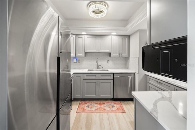 8750 Midnight Pass Rd Unit 501, Sarasota, FL 34242 - kitchen featuring appliances with stainless steel finishes, backsplash, light wood-style flooring, light stone counters, and gray cabinetry