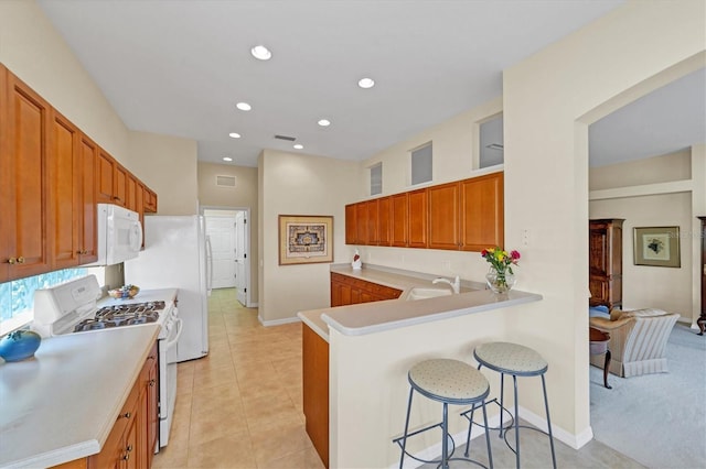 5179 Cantabria Crst, Sarasota, FL 34238 - kitchen featuring white appliances, a kitchen breakfast bar, light countertops, brown cabinetry, and recessed lighting
