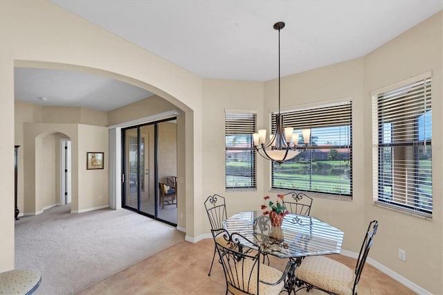 5179 Cantabria Crst, Sarasota, FL 34238 - dining space featuring a chandelier, arched walkways, light tile patterned floors, and light colored carpet