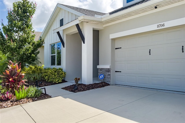 8706 Arrow Creek Dr, Parrish, FL 34219 - view of exterior entry featuring board and batten siding, roof with shingles, concrete driveway, and stone siding