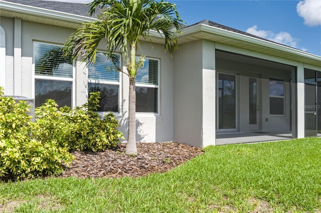 8706 Arrow Creek Dr, Parrish, FL 34219 - view of side of property featuring stucco siding, a lawn, roof with shingles, and a sunroom