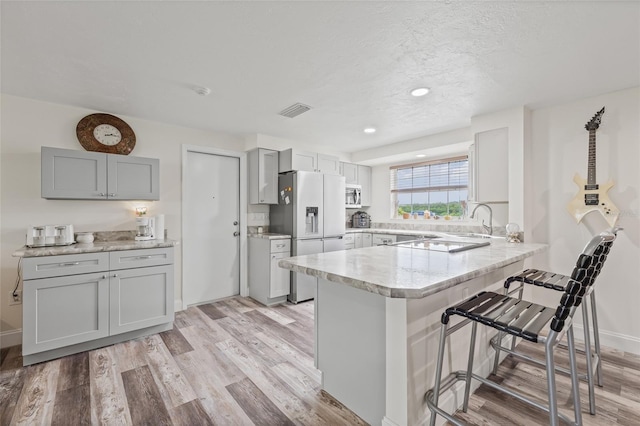 336 Highland Shores Dr, Ellenton, FL 34222 - kitchen featuring stainless steel fridge, a peninsula, a breakfast bar area, light wood-style flooring, and recessed lighting