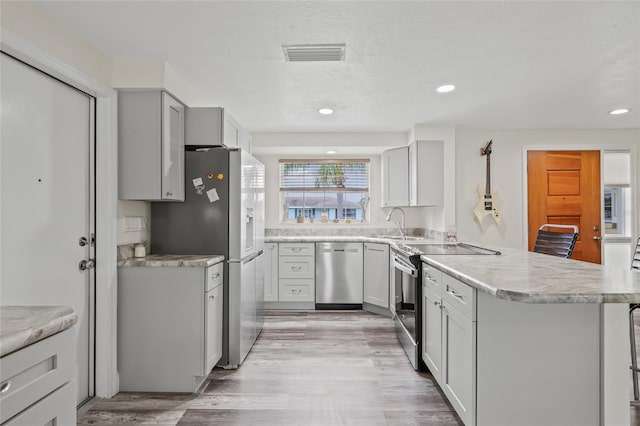 336 Highland Shores Dr, Ellenton, FL 34222 - kitchen featuring appliances with stainless steel finishes, a peninsula, light countertops, light wood-type flooring, and recessed lighting