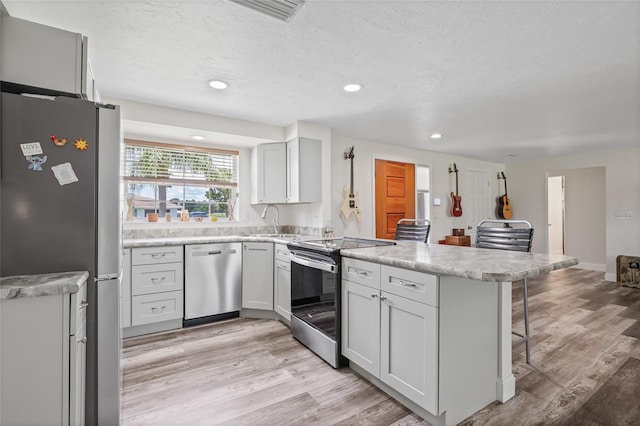 336 Highland Shores Dr, Ellenton, FL 34222 - kitchen featuring stainless steel appliances, a peninsula, a kitchen breakfast bar, light countertops, and light wood-type flooring