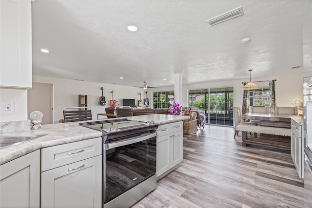 336 Highland Shores Dr, Ellenton, FL 34222 - kitchen with stainless steel electric range, open floor plan, white cabinets, light wood-style flooring, and light countertops