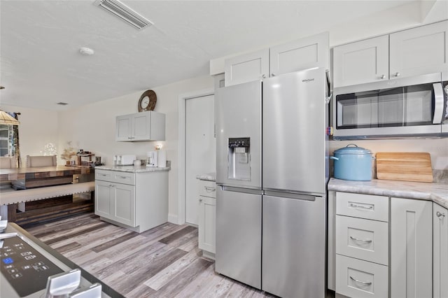 336 Highland Shores Dr, Ellenton, FL 34222 - kitchen with stainless steel appliances, light wood-type flooring, and white cabinetry