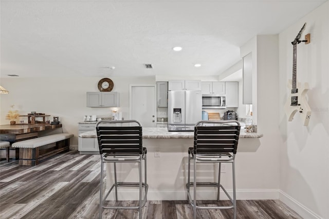 336 Highland Shores Dr, Ellenton, FL 34222 - kitchen with stainless steel microwave, refrigerator with ice dispenser, a peninsula, dark wood-type flooring, and a breakfast bar area
