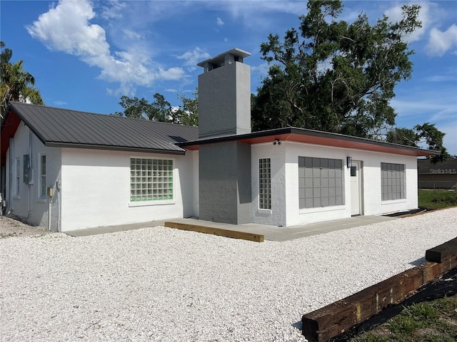 4122 N Lockwood Ridge Rd, Sarasota, FL 34234 - rear view of property featuring a chimney, stucco siding, a metal roof, and a patio area