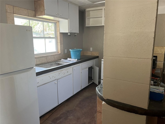 4122 N Lockwood Ridge Rd, Sarasota, FL 34234 - kitchen with freestanding refrigerator, dark countertops, concrete flooring, white cabinetry, and open shelves