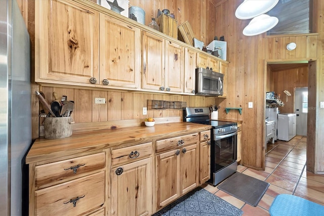 39700 State Road 70 E, Myakka City, FL 34251 - kitchen featuring stainless steel appliances, butcher block countertops, wood walls, washer and dryer, and light tile patterned floors