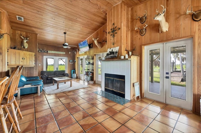 39700 State Road 70 E, Myakka City, FL 34251 - tiled living area with french doors, wood ceiling, wooden walls, a tiled fireplace, and ceiling fan