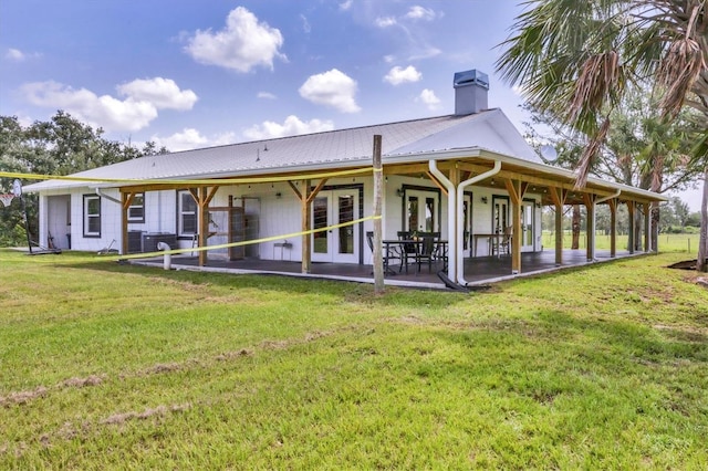 39700 State Road 70 E, Myakka City, FL 34251 - back of house featuring french doors, a chimney, a lawn, a patio area, and a metal roof