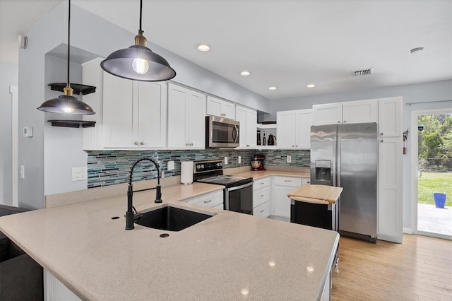 1778 N Salford Blvd, North Port, FL 34286 - kitchen featuring stainless steel appliances, a peninsula, white cabinets, tasteful backsplash, and light wood-style flooring