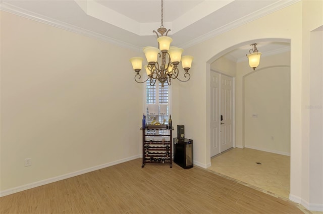 6610 Rosy Barb Ct, Lakewood Ranch, FL 34202 - unfurnished room with arched walkways, a chandelier, wood finished floors, a tray ceiling, and crown molding