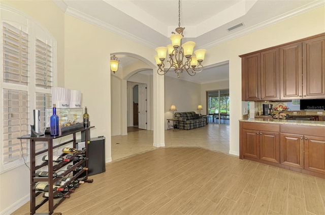 6610 Rosy Barb Ct, Lakewood Ranch, FL 34202 - kitchen with arched walkways, a chandelier, a raised ceiling, light wood-style flooring, and crown molding