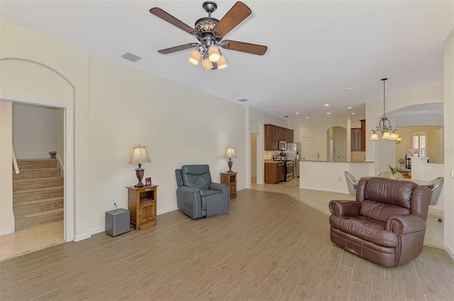 6610 Rosy Barb Ct, Lakewood Ranch, FL 34202 - living room with arched walkways, light wood-style flooring, a ceiling fan, stairs, and a chandelier