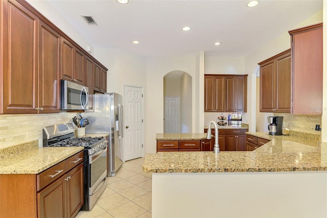 6610 Rosy Barb Ct, Lakewood Ranch, FL 34202 - kitchen with stainless steel appliances, arched walkways, a peninsula, light tile patterned flooring, and light stone counters
