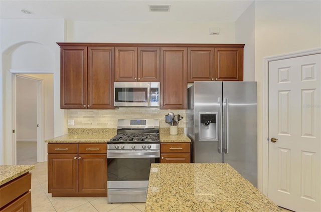 6610 Rosy Barb Ct, Lakewood Ranch, FL 34202 - kitchen featuring stainless steel appliances, backsplash, light stone counters, and light tile patterned floors