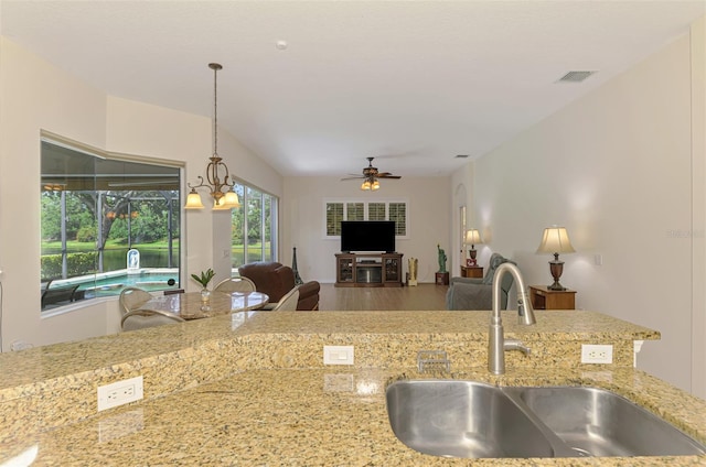6610 Rosy Barb Ct, Lakewood Ranch, FL 34202 - kitchen with ceiling fan, hanging light fixtures, light stone countertops, wood finished floors, and open floor plan