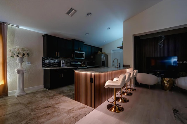 3524 Brownwood Ter, North Port, FL 34286 - kitchen featuring stainless steel appliances, a breakfast bar, vaulted ceiling, backsplash, and a peninsula