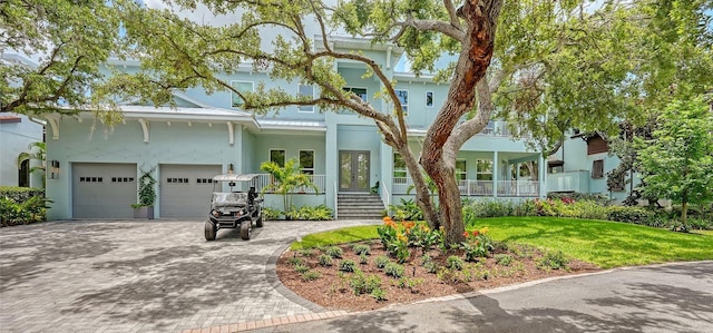 1076 Toc0Baga, Sarasota, FL 34234 - view of front of house featuring decorative driveway, stucco siding, covered porch, a garage, and a front yard