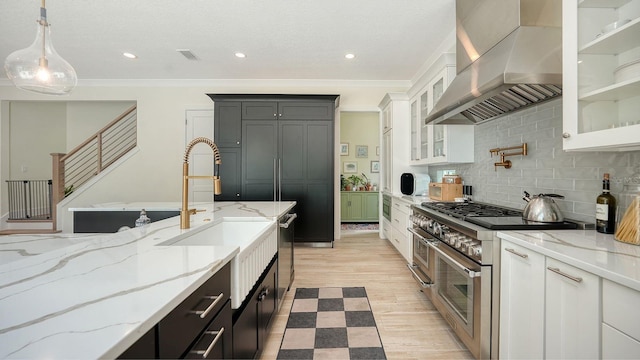 1076 Toc0Baga, Sarasota, FL 34234 - kitchen with wall chimney exhaust hood, double oven range, decorative backsplash, light stone counters, and decorative light fixtures