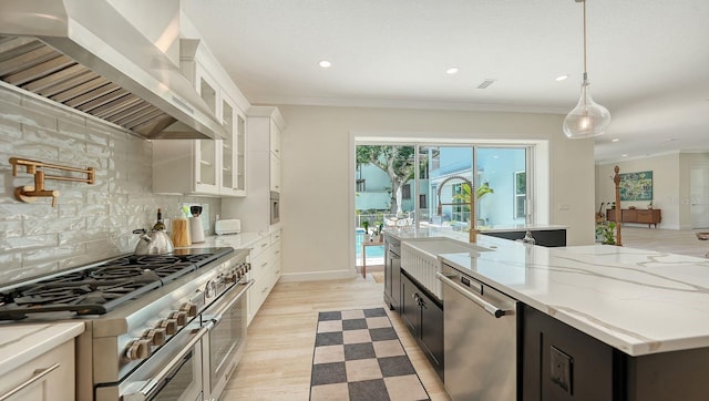 1076 Toc0Baga, Sarasota, FL 34234 - kitchen with appliances with stainless steel finishes, wall chimney exhaust hood, white cabinets, light stone countertops, and backsplash