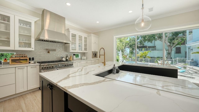 1076 Toc0Baga, Sarasota, FL 34234 - kitchen featuring wall chimney range hood, backsplash, white cabinetry, pendant lighting, and ornamental molding