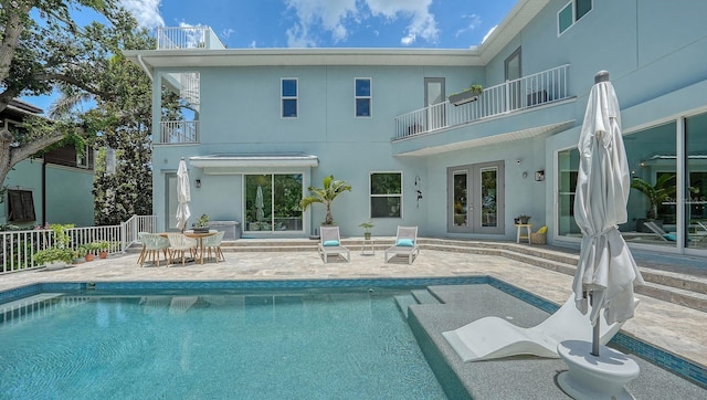 1076 Toc0Baga, Sarasota, FL 34234 - rear view of property featuring a balcony, french doors, a patio, an outdoor pool, and stucco siding